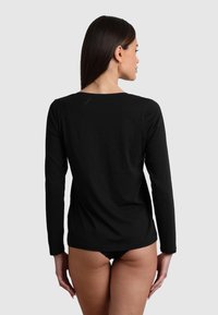 Maglietta nera a maniche lunghe realizzata in materiale morbido, con scollo rotondo e design semplice, vista da dietro.