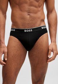 Schwarze Baumwollunterhose mit einem bequemen elastischen Bund, der das "BOSS"-Logo in Weiß zeigt. Angenehme Textur und unterstützendes Design.