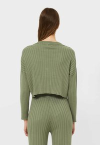 Pull en maille côtelée vert olive, avec une coupe courte et des manches longues, présentant un col large et une finition texturée.