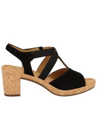 Sandale en daim noir avec un talon fermé, des brides élastiques croisées, un design à bout ouvert, et un talon bloc en liège pour plus de stabilité.