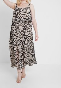 Robe longue en tissu transparent avec imprimé zèbre beige et noir. Bretelles spaghetti, corsage à couches superposées et fentes latérales pour faciliter les mouvements.