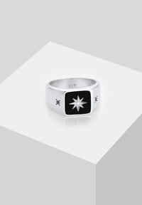 Anello d'argento con una pietra nera rettangolare decorata con un motivo a stella. Incisioni ornamentali sulla fascia. Contrassegnato '925' per argento sterling.