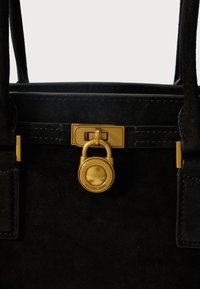 Schwarze Wildleder-Handtasche mit goldenem Vorhängeschlossverschluss, rechteckiger Form, gesteppten Details und doppelten Tragegriffen.