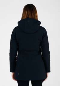 Cappotto isolante blu navy con forma aderente, cappuccio e texture liscia. Presenta un dettaglio con bottone al collo e tasche laterali nascoste.