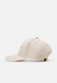 Beige sapka ívelt napellenzővel, pamutból készült. Az elején hímzett logó található, és az oldalán egy kis fekete címke.