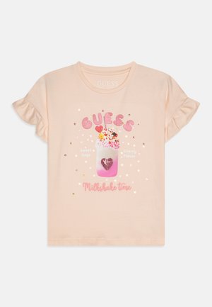 Camiseta de manga corta color durazno con mangas con volantes, que presenta un gráfico de batido decorado con lentejuelas rosas y texto en rosa y dorado.