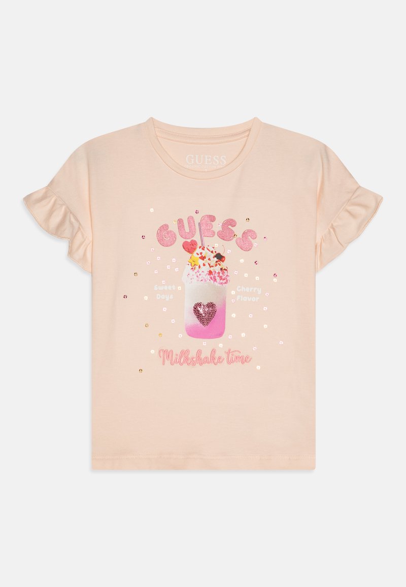 Kortermet ferskenfarget t-skjorte med volanger, som har et melkeshake-motiv dekorert med rosa paljetter og tekst i rosa og gull.