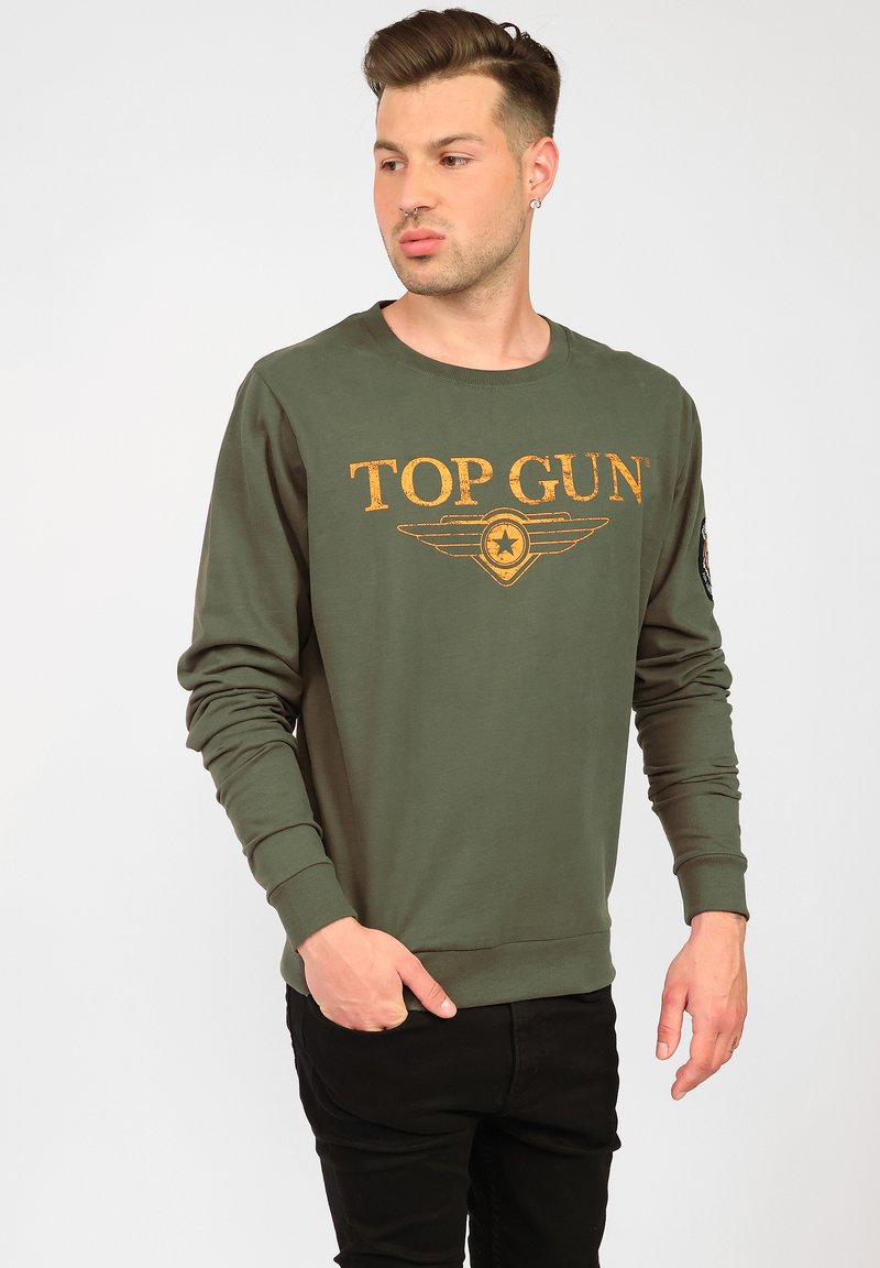 Olivgrön sweatshirt i bomull med långa ärmar, som har en sliten "TOP GUN"-logotyp i gult och en flygande vinge grafik på bröstet.
