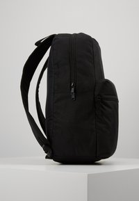 Zaino nero con forma rettangolare, realizzato in tessuto resistente. Caratterizzato da un compartimento principale con zip e una piccola tasca laterale con zip.