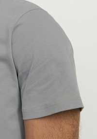 Camiseta gris de manga corta con una textura suave. Presenta un escote redondo y un dobladillo cosido, que demuestran un ajuste relajado.