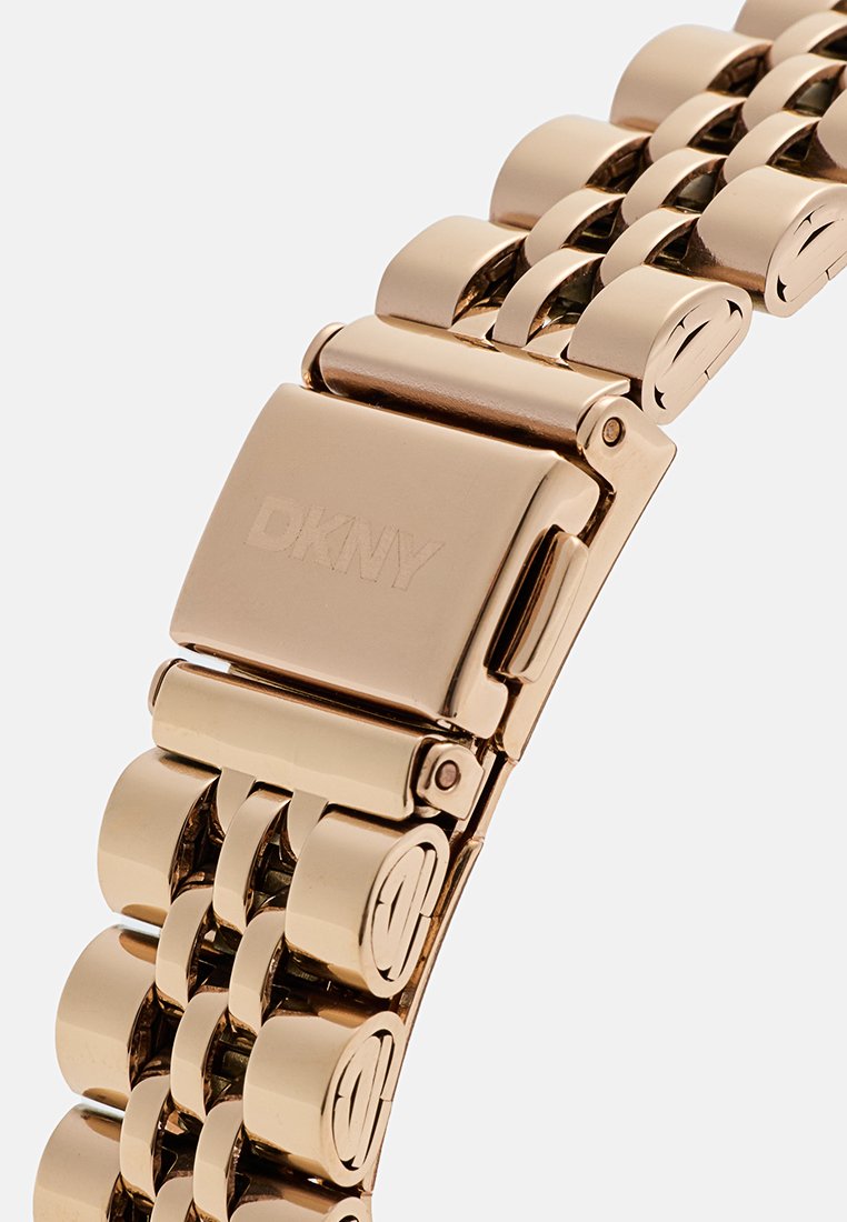 Goldfarbene Edelstahl-Uhr mit einem Gliederarmband, das mit einem Verschluss mit der Gravur "DKNY" versehen ist. Glatte, polierte Oberfläche; abgerundete Glieder.