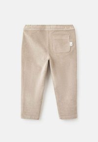 Pantaloni din bumbac bej cu talie elastică, design drept, și un singur buzunar pe spate cu un eticheta în colț.