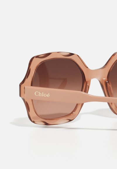 Brūnganā tonī saulesbrilles ar masīvu astoņstūra akrila rāmi un zeltītu "Chloé" logotipu uz gaiši brūnā tempļa.