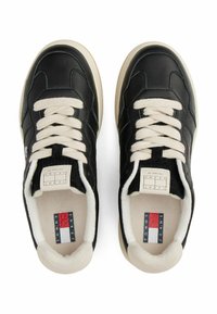 Czarne skórzane sneakersy z kremowymi sznurowadłami i podszyciem, okrągły nos, biały środkowy podeszwa oraz mały detal logo w kolorach czerwonym, białym i niebieskim.