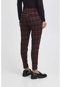 Geruite broek in bordeauxrood en groen. Elastische tailleband, slim fit, met achterzak. Gecombineerd met zwarte lakleren loafers.