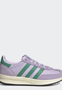 Zapatilla Adidas de color lila claro con rayas verdes, cordones blancos, suela acolchada color crema y suela exterior texturizada negra sobre fondo gris.