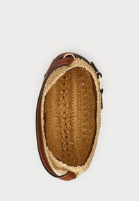 Brūna ādas rokassoma ar austu salmu iekšpusi. Iespējas ietver noapaļotu formu un plānu siksniņu, izceļot maiņus tekstūrās un krāsās.