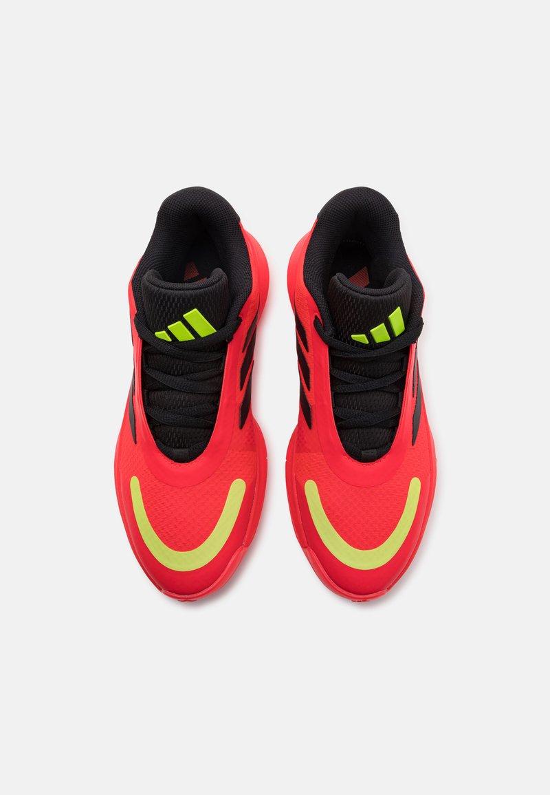 Baskets de sport rouges avec une tige en maille noire respirante, des accents jaunes vifs et une semelle extérieure lisse et arrondie. Présente trois rayures noires.