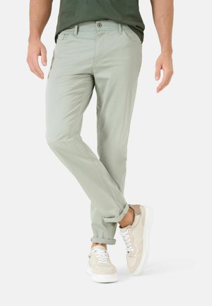 Lichtgroene chino's gemaakt van zachte stof, met een slim fit, opgerolde mouwen en zijzakken. Gecombineerd met beige en witte sneakers.