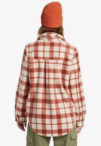 Flannel shirt in cream with large red and brown checks, featuring a spread collar and long sleeves. Worn with an orange knitted beanie.