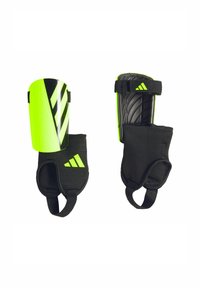 Green and black shin guards with striped design, adjustable straps, and padded fabric. Features a protective plastic front and textured back.