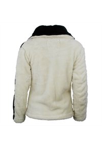 Veste crème duveteuse avec un col et des bordures noirs, dotée de longs manches et d'une finition douce et texturée, conçue pour la chaleur et le confort.