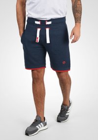 Diepblauwe shorts van een zachte katoenmix, met een rode bies, dubbele trekkers en een klein logo aan de linkerkant. Gevoelige oppervlakte.