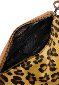 Binnenkant van een tan leren tas met een leopardprint patroon en zwarte voering met het "Venezia" logo. Bevat een klein zwart ritsvakje.