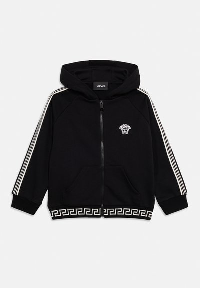 Μαύρο φούτερ με φερμουάρ και κουκούλα, λευκό λογότυπο Μέδουσας στο στήθος, λευκές ρίγες στα μανίκια και μοτίβο ελληνικού κλειδιού κατά μήκος του κάτω τελειώματος.