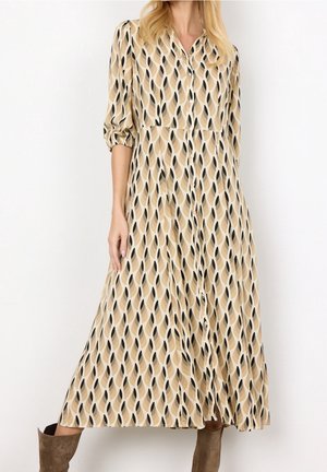 Langes, knöpfbares Kleid aus leichtem Stoff mit beige Grundfarbe und schwarzen sowie braunen Blattmustern; dreiviertellange Ärmel und lockere Passform.