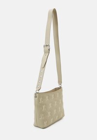 Sac bandoulière beige avec motif logo embossé, bandoulière réglable avec quincaillerie argentée, texture douce et forme rectangulaire.