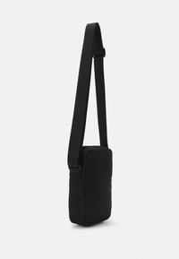 Borsa a tracolla nera in tessuto, di forma rettangolare, con tracolla regolabile, texture liscia e design minimalista. Nessun hardware o accento visibile.