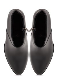 Paire de bottines en cuir noir avec fermetures éclair latérales, bouts pointus et petits talons, vues de dessus sur fond blanc.