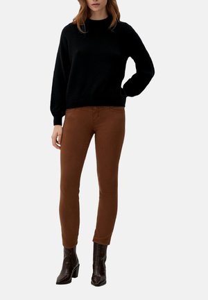 Zwarte gebreide trui met lange mouwen, gecombineerd met aansluitende bruine broek. Model draagt glanzende bruine enkellaarsjes met een gestructureerde afwerking.