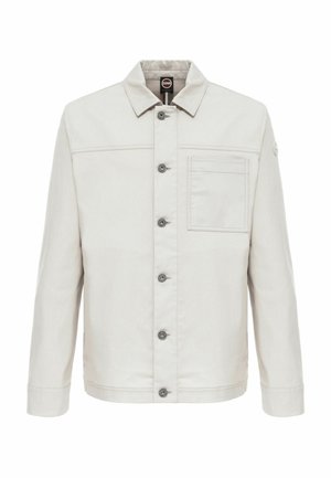 Chaqueta beige claro abotonada con cuello, mangas largas, bolsillo en el pecho a la izquierda y un pequeño logo redondo en la parte superior de la manga izquierda.