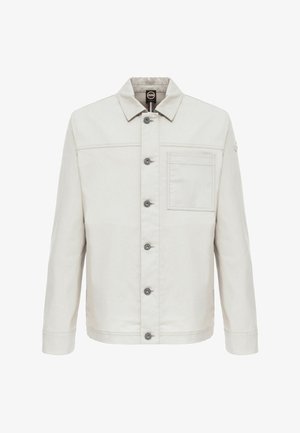 Világos bézs gombos dzseki gallérral, hosszú ujjakkal, bal oldalon mellzsebbel és egy kis kerek logóval a bal felső ujjrészen.