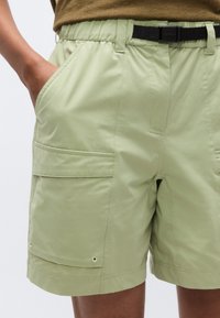Ελαφριά πράσινα cargo σορτς από λείο ύφασμα, με διπλές πλαϊνές τσέπες, ρυθμιζόμενο μαύρο ζωνάρι και ασφαλές κλείσιμο στη μέση.