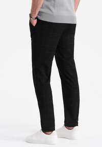 Pantalons à carreaux noirs en tissu doux, à coupe slim et dotés de deux poches latérales, assortis à des baskets blanches.