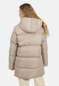 Jasnobeżowa kurtka puchowa z kapturem, z pikowanymi sekcjami i lekko zaokrąglonym hemem. Gładki, błyszczący materiał zewnętrzny.