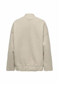 Kergedest fliisi jope heles beež, millel on tekstuuriga pind, madalad õlad ja ümmargune kaelus. Õmblusdetail kulgeb mööda selga.