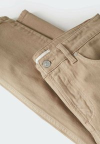 Beige Baumwollhosen gefaltet, mit einem Metallknopf, einer Fronttasche und Steppdetails. Der Stoff zeigt eine glatte Textur und ein lässiges Design.