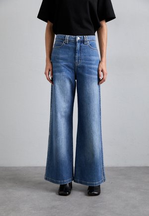 Jeans lejera decolorata, cu picioare largi, din denim, avand talie inalta, design traditional cu cinci buzunare si cusaturi in contrast.