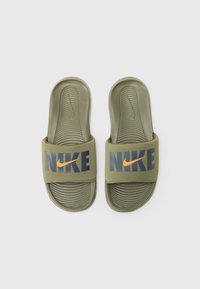 Chanclas de color verde oliva con una base texturizada, que cuentan con un gran logo gris de "NIKE" y un diseño de swoosh naranja en la correa.