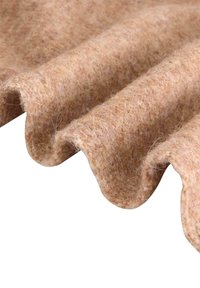 Filtmaterial i mjuk beige med en vågig kant, som visar en texturerad yta och fina fibrer, lämplig för hantverk eller tapetsering.