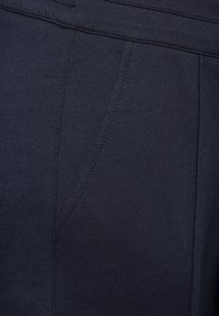 Mörk marinblått tyg med en slät textur, med subtila sömnadsdetaljer och en byxdessign med sidofickor.