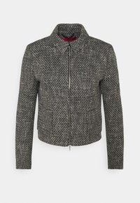 Chaqueta texturizada en blanco y negro con cuello con solapa, cierre frontal con cremallera y mangas largas. El tejido presenta un patrón tejido.