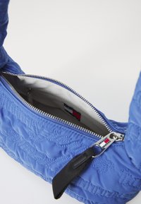 Borsa a spalla blu trapuntata con apertura con cerniera, accessori in argento e un interno liscio con etichetta del marchio.