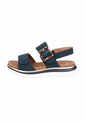 Black open-toe sandal with adjustable strap and tortoiseshell buckle, cushioned brown footbed, and white rubber sole with black trim.
