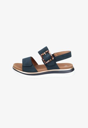 Black open-toe sandal with adjustable strap and tortoiseshell buckle, cushioned brown footbed, and white rubber sole with black trim.