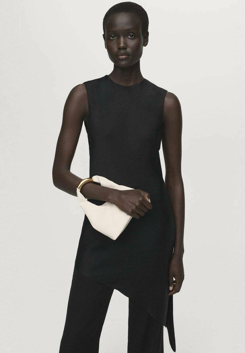 Abito nero senza maniche con orlo asimmetrico, abbinato a una borsa a pochette bianca. Il tessuto sembra liscio, creando una silhouette elegante.